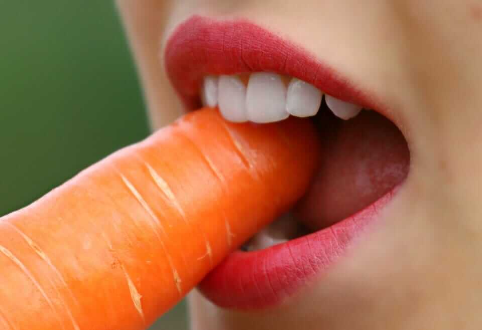 someone eating a carrot to reduce plaque